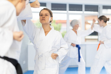 Obraz premium Concentrated young woman in kimono honing punching techniques during kumite with female opponent at karate training session