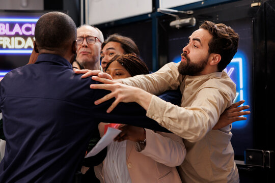 Black Friday chaos. Aggressive violent shoppers fighting with security officer while waiting in line for sales at shopping mall entrance, angry diverse people trying to enter store before doors open