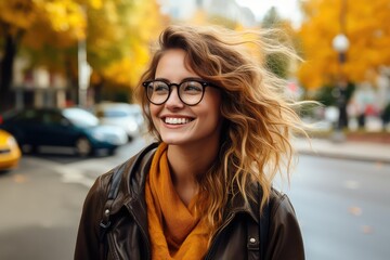 Fototapeta premium Uśmiechnięta studentka w okularach i z plecakiem, spacerująca po ulicach miasta. 
