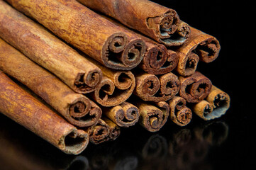 A pile of cinnamon sticks on a black background