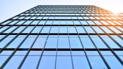 Fototapeta na wymiar Looking up blue modern office building. The glass windows of building with aluminum framework.