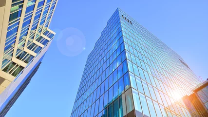 Fotobehang Looking up blue modern office building. The glass windows of building with  aluminum framework. © Grand Warszawski