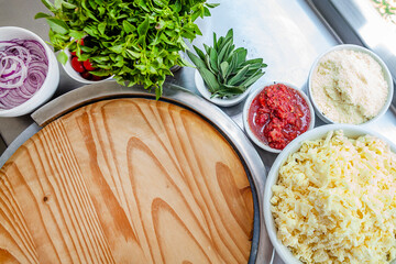 Pizza chef bench top view with ingredients background close up basil, tomatoes, onions