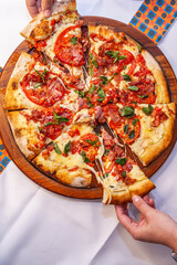 Taking slice of pizza top view with close up with melted cheese