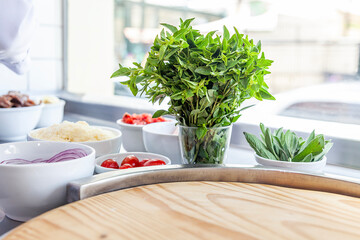Pizza restaurant bench with pizza ingredients basil tomatoes, onions close up with window background