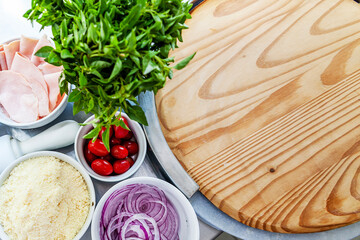 Pizza restaurant bench with pizza ingredients basil tomatoes, onions close up with window background