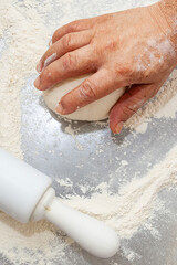Chef hand working on dough top view close up with flour background