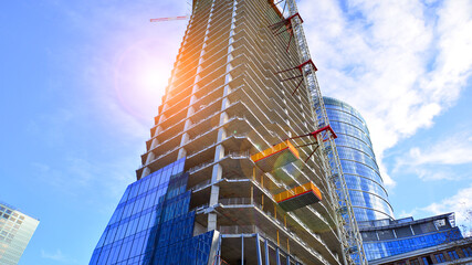 High rise building under construction. Installation of glass facade panels on a reinforced concrete...