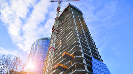 High rise building under construction. Installation of glass facade panels on a reinforced concrete...