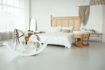 large bright bedroom with white walls and a large bed with a white knitted bedspread. near the bed...