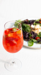Copa de sangría con ensalada de fondo 