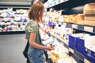 Pretty girl child choosing yogurt in supermarket. Beautiful female preteen kid looking milk products in grocery store
