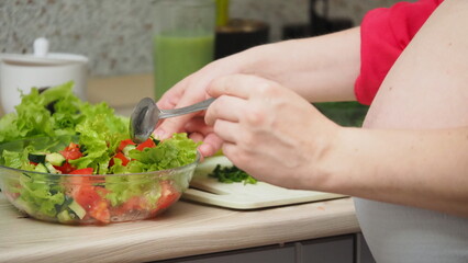 Beautiful Pregnant Woman Happily Preparing a Vegetable Salad, Organic Healthy Food, in a Cozy Home Kitchen. The Concept Of Diet, Proper Nutrition, Healthy Pregnancy and People.