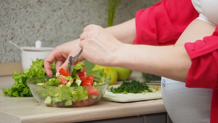 Beautiful Pregnant Woman Happily Preparing a Vegetable Salad, Organic Healthy Food, in a Cozy Home Kitchen. The Concept Of Diet, Proper Nutrition, Healthy Pregnancy and People.