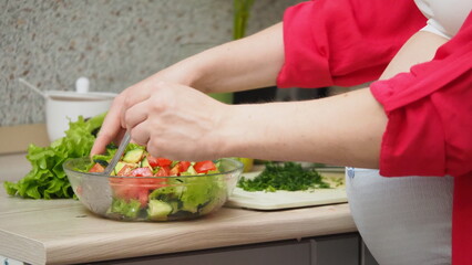 Beautiful Pregnant Woman Happily Preparing a Vegetable Salad, Organic Healthy Food, in a Cozy Home Kitchen. The Concept Of Diet, Proper Nutrition, Healthy Pregnancy and People.