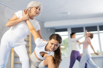 Fototapeta premium Elderly woman and young woman training self-defense techniques in group in studio