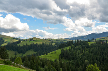 Fototapeta na wymiar Mountain slopes, trees and clouds in the sky. Amazing landscape view of Ukrainian Carpathian mountains