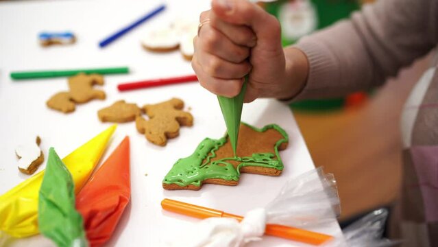 Chef applying green icing to Christmas tree shaped cookies