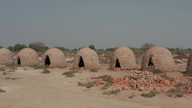 Footage showing a rwo of kilns structures for local production of biochar in the village