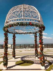 a gazebo decorated for christmas with garlands and holly tree