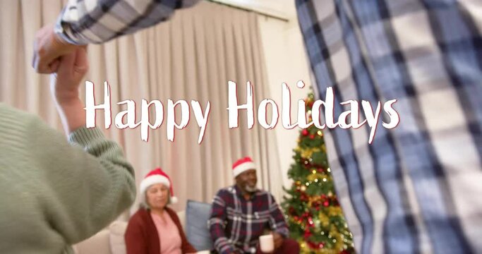 Animation of happy holidays text over diverse senior friends dancing at christmas at home