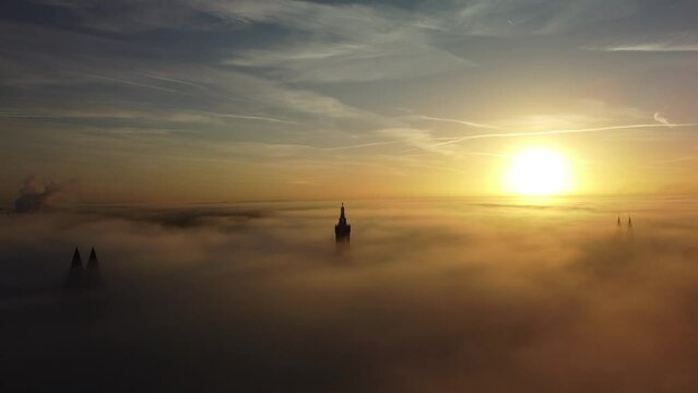 Aerial footage of St. Christopher Cathedral bell tower and Natalini-Toren among dense fog at sunrise