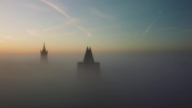 Drone footage of the top of architectures of Roermond city in fog at sunset