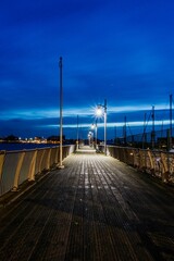 Naklejka premium Wooden pier stretching into the distance during the early evening hours, illuminated by lights
