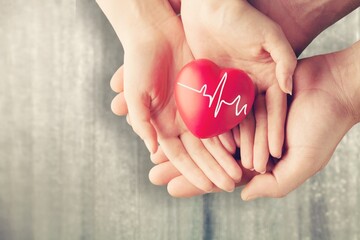 Man and woman holding red heart on background