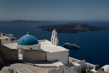 Fototapeta na wymiar Beautiful blue domed church over the water in Santorini, Greece