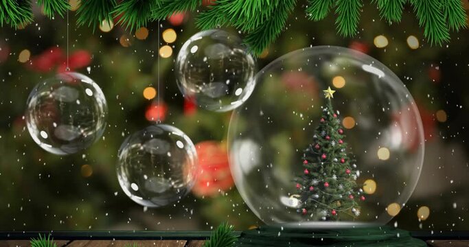 Animation of branch and snow falling on christmas tree in a snowglobe and hanging bauble decorations