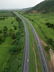 Aerial view of a tree-lined highway leading to a vast expanse of green grass in the distance