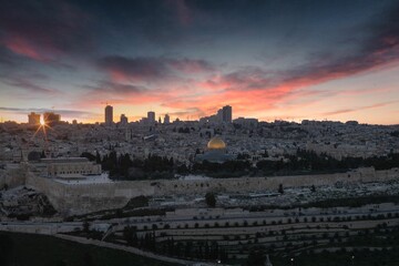Fototapeta premium sunset over the dome of the rock with buildings and green lawn below