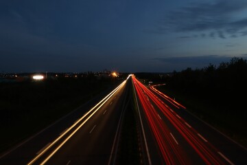 Obraz premium Long exposure shot of glowing car lights on a dark highway