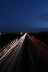 Fototapeta na wymiar Vertical long exposure shot of glowing car lights on a dark highway