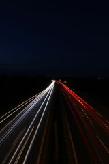 Vertical long exposure shot of glowing car lights on a dark highway