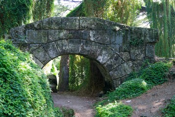 Fototapeta na wymiar Stone bridge over the dirt road in the park