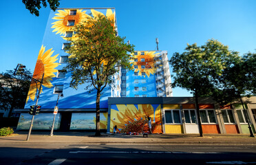 artistically painted house, skyscraper with sunflower blossoms on blue house wall, mural painting,...