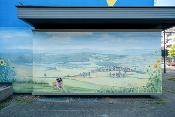 part of an artistically painted blue house with painted landscape with a Leonberger Dog, mural...