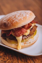 Closeup shot of an appetizing burger with bacon and cheese on a white plate.