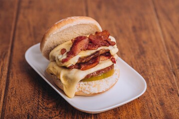 Closeup shot of an appetizing burger with bacon and cheese on a white plate.