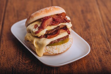 Closeup shot of an appetizing burger with bacon and cheese on a white plate.