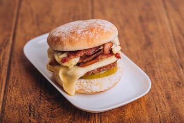 Closeup shot of an appetizing burger with bacon and cheese on a white plate.