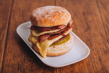 Closeup shot of an appetizing burger with bacon and cheese on a white plate.