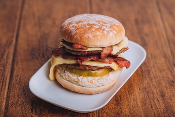 Closeup shot of an appetizing burger with bacon and cheese on a white plate.