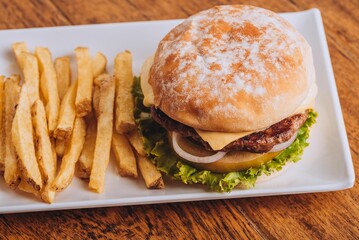 Closeup shot of a delicious hamburger with French fries on a wooden table.