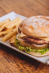 Closeup shot of a delicious hamburger with French fries on a wooden table.