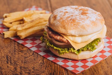 Closeup shot of a delicious hamburger with French fries on a wooden table.