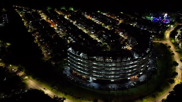 Drone footage over illuminating round modern building at night in the city