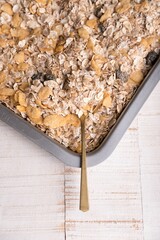 Close-up image of dry oatmeal and a spoon in a gray sheet pan
